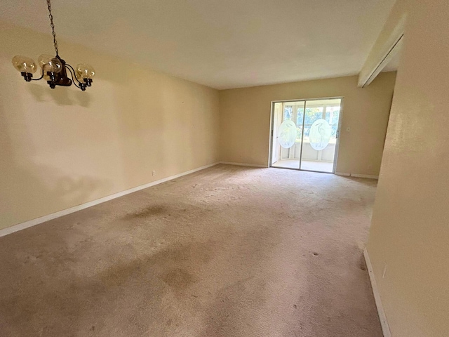 carpeted spare room featuring a notable chandelier