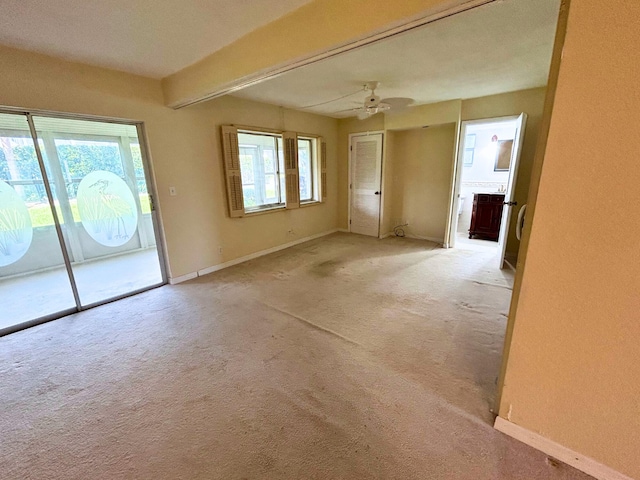 carpeted spare room with ceiling fan and beamed ceiling