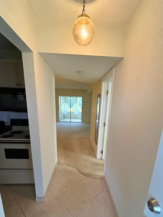 hallway featuring vaulted ceiling, a textured ceiling, and light tile patterned floors