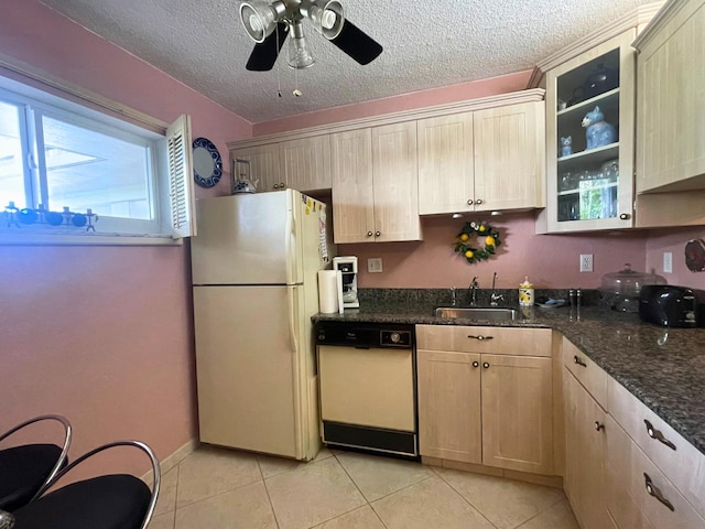 kitchen with dishwashing machine, sink, white fridge, dark stone counters, and a textured ceiling