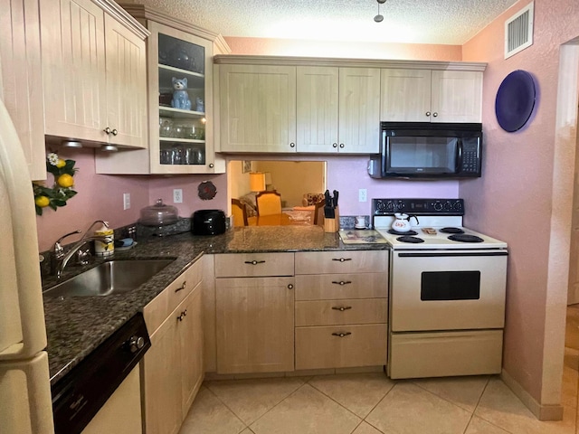 kitchen with light tile patterned flooring, white appliances, dark stone counters, sink, and a textured ceiling