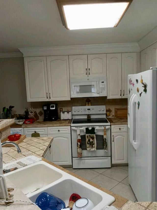 kitchen with light tile flooring, white appliances, white cabinets, tile countertops, and ornamental molding