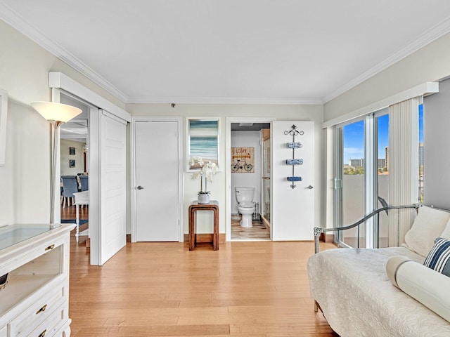 bedroom with connected bathroom, crown molding, and light hardwood / wood-style flooring