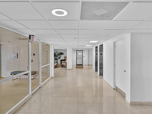 corridor with light tile patterned floors and a drop ceiling