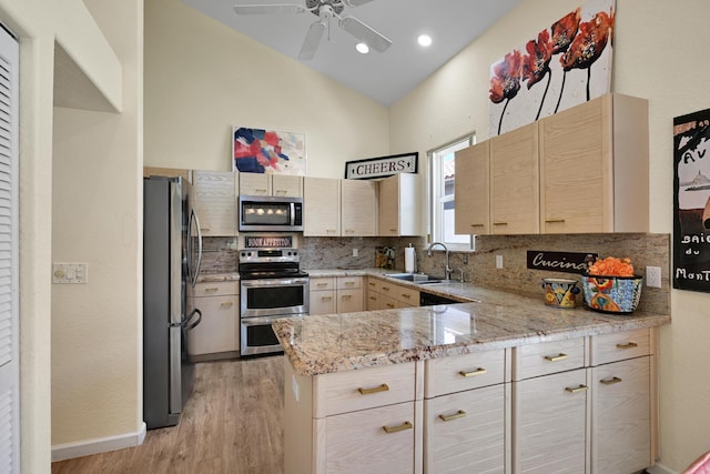 kitchen featuring a ceiling fan, a peninsula, light wood-style floors, a sink, and appliances with stainless steel finishes