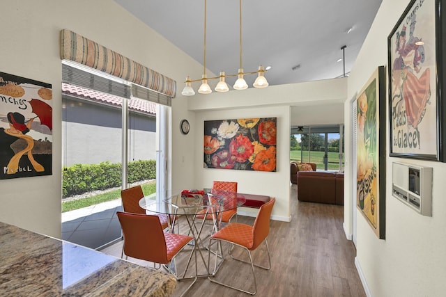 dining area featuring baseboards, wood finished floors, and vaulted ceiling