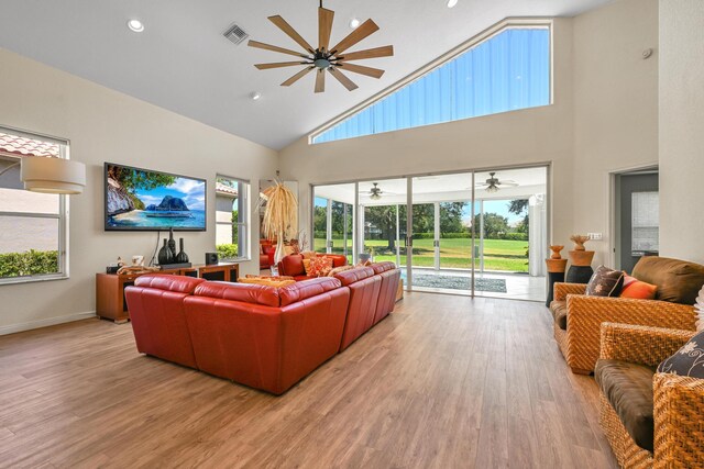 living area featuring high vaulted ceiling, ceiling fan, light wood-style flooring, and visible vents