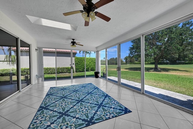 unfurnished sunroom with a ceiling fan, a wealth of natural light, and a skylight