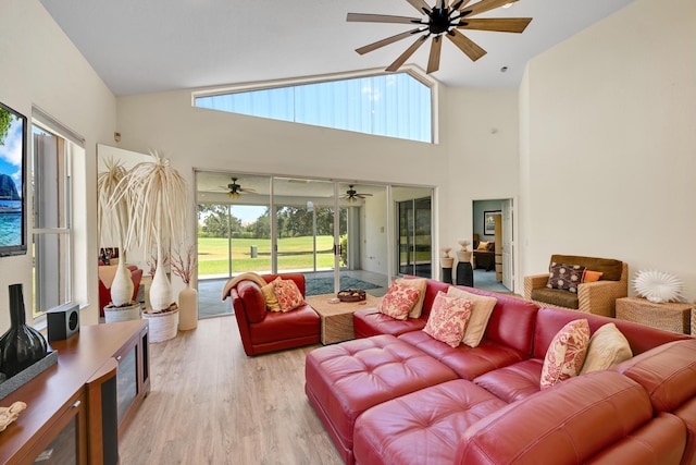 living room with high vaulted ceiling, ceiling fan, and light wood-style flooring