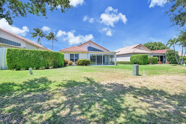 view of front of property with a sunroom, a front lawn, stucco siding, and a tile roof