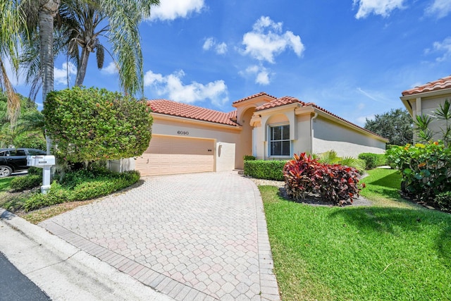mediterranean / spanish house featuring an attached garage, stucco siding, a front yard, decorative driveway, and a tiled roof
