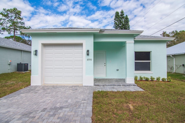 view of front of home featuring a garage, a front yard, and central air condition unit