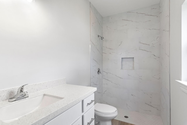 bathroom featuring vanity, tiled shower, and toilet