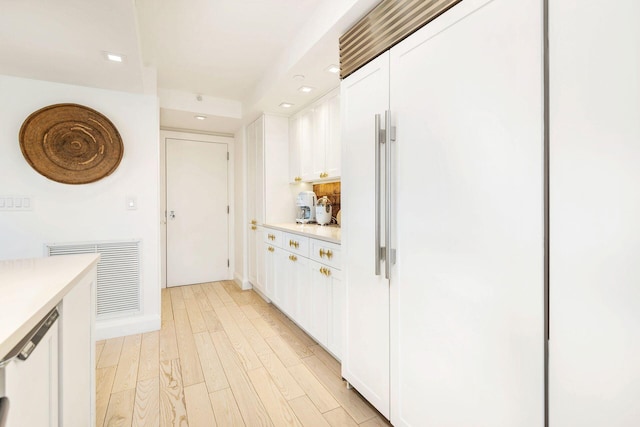 kitchen featuring white cabinetry, paneled refrigerator, and light wood-type flooring