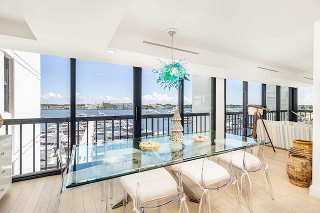 dining space with plenty of natural light, a wall of windows, light hardwood / wood-style floors, and a water view