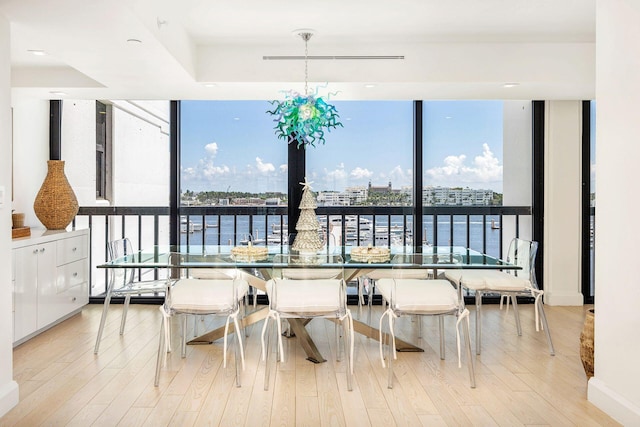 dining space with expansive windows, a water view, and light hardwood / wood-style flooring