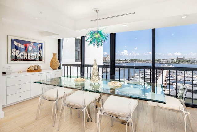 dining room featuring a water view, expansive windows, and light wood-type flooring