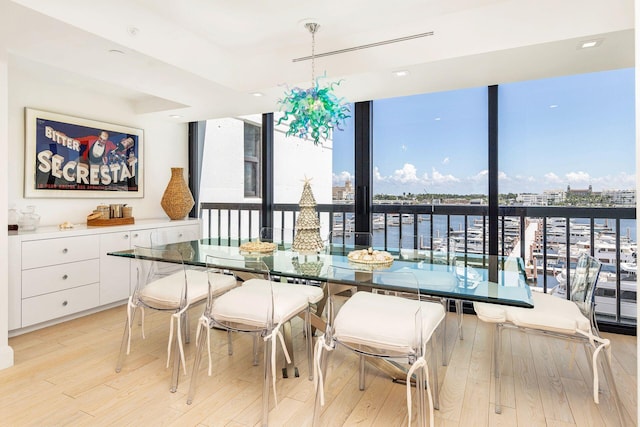 dining area with floor to ceiling windows, a water view, and light wood-type flooring