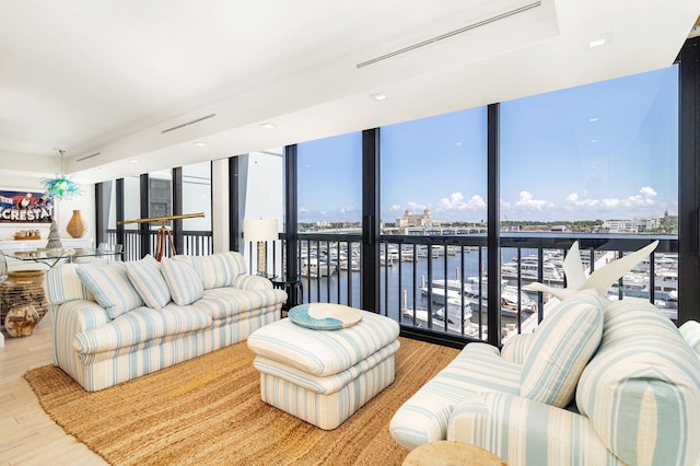 living room featuring a water view, expansive windows, and light wood-type flooring