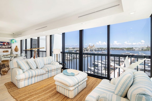 living room with a water view, light hardwood / wood-style flooring, and a wall of windows