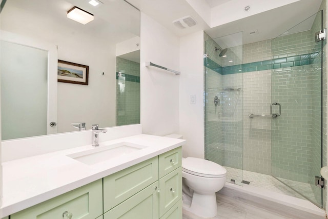 bathroom with hardwood / wood-style floors, toilet, a shower with door, and vanity with extensive cabinet space