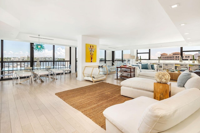 living room featuring plenty of natural light, expansive windows, light hardwood / wood-style floors, and a notable chandelier