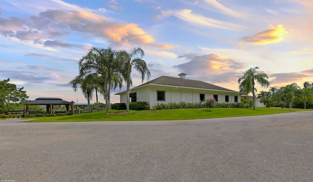 property exterior at dusk featuring a gazebo and a lawn