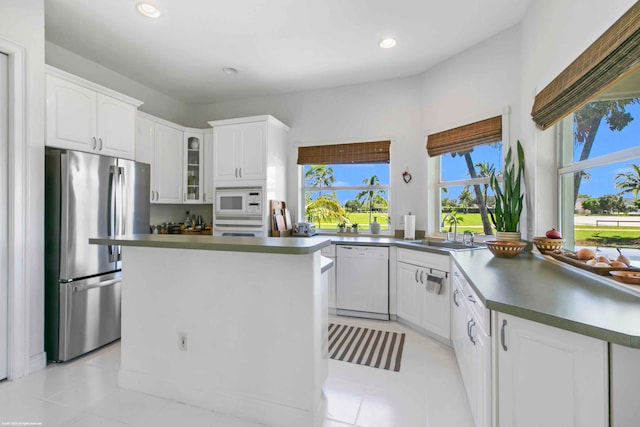 kitchen featuring light tile floors, a center island, white appliances, white cabinets, and sink