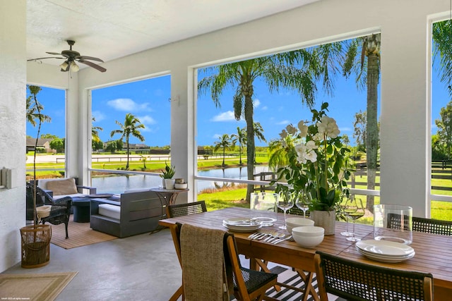 sunroom / solarium with a water view, a healthy amount of sunlight, and ceiling fan