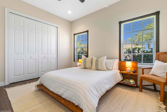 bedroom featuring a closet, wood-type flooring, ceiling fan, and multiple windows