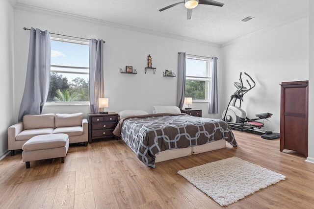 bedroom with crown molding, a textured ceiling, ceiling fan, and light hardwood / wood-style floors