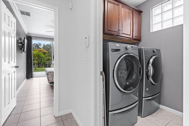 washroom featuring light tile patterned floors, crown molding, washer and clothes dryer, cabinets, and a textured ceiling