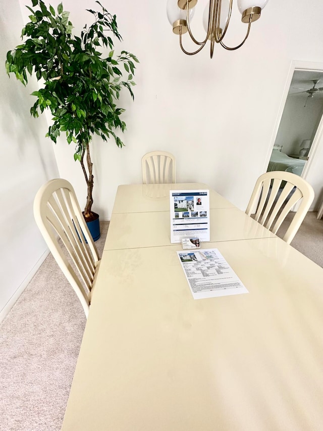 carpeted dining space featuring ceiling fan with notable chandelier