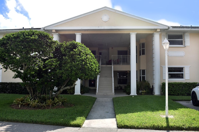 greek revival house featuring a balcony and a front lawn