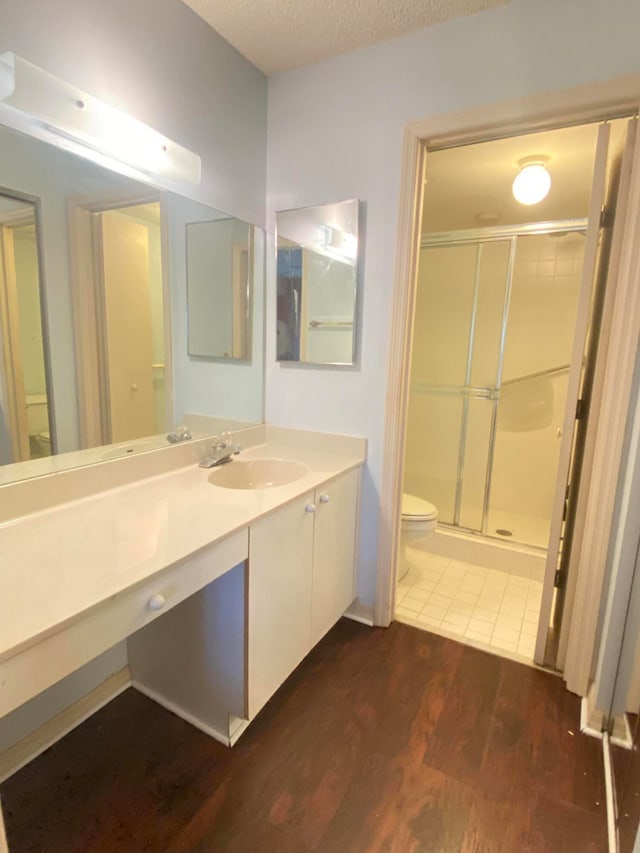 bathroom featuring hardwood / wood-style floors, oversized vanity, toilet, and walk in shower