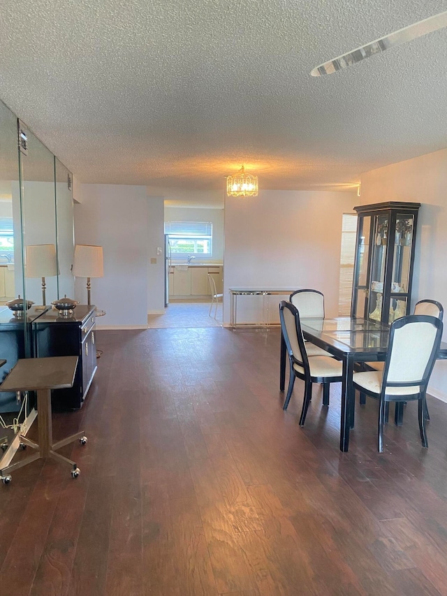 dining room featuring an inviting chandelier, a textured ceiling, and dark hardwood / wood-style flooring