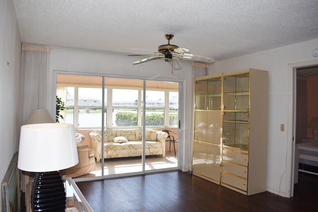 interior space with ceiling fan, a textured ceiling, and dark wood-type flooring