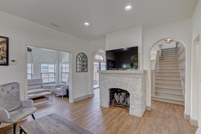 living room with a stone fireplace and light hardwood / wood-style flooring