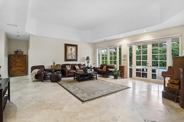 living room featuring a tray ceiling, french doors, and light tile flooring