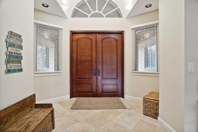 foyer entrance featuring light tile floors and vaulted ceiling