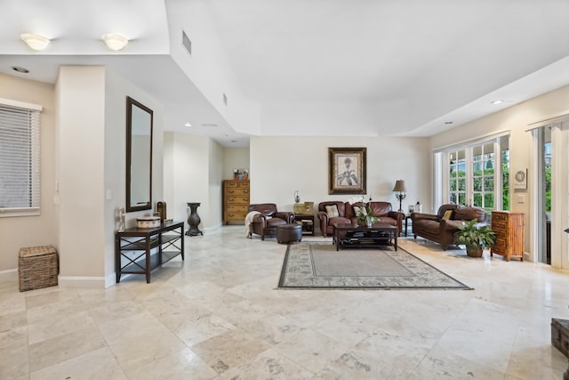 living room with a tray ceiling and light tile flooring