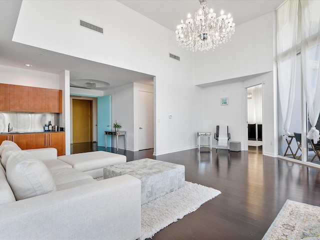 living room with an inviting chandelier, sink, dark hardwood / wood-style flooring, and a high ceiling