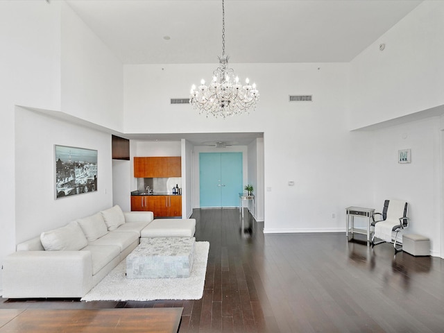 living room featuring a notable chandelier, a towering ceiling, and dark hardwood / wood-style flooring