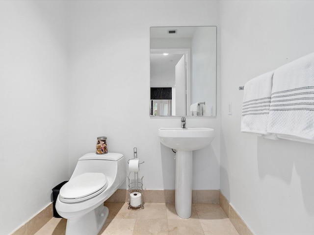 bathroom with toilet, tile flooring, and sink