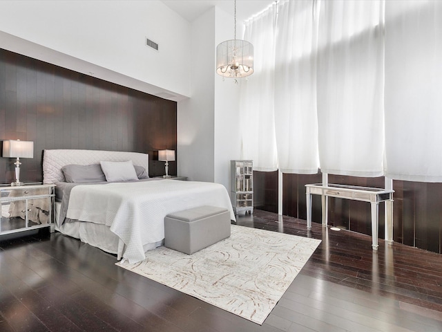 bedroom with a chandelier, a high ceiling, and dark hardwood / wood-style flooring