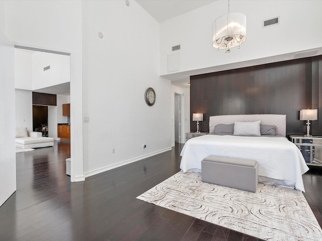 bedroom with dark hardwood / wood-style flooring, a chandelier, and a towering ceiling