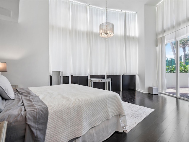 bedroom with access to exterior, a chandelier, and dark wood-type flooring