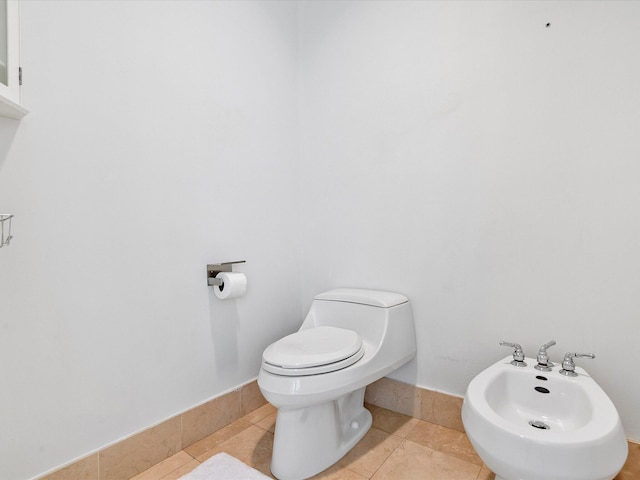 bathroom with a bidet, toilet, and tile floors