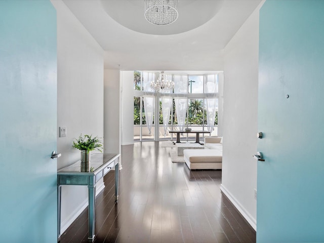 corridor with dark wood-type flooring and an inviting chandelier