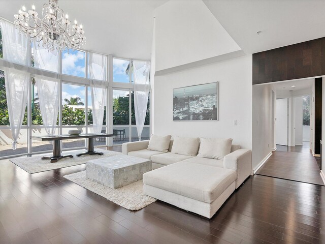 living room featuring an inviting chandelier, dark hardwood / wood-style floors, a high ceiling, and a wall of windows